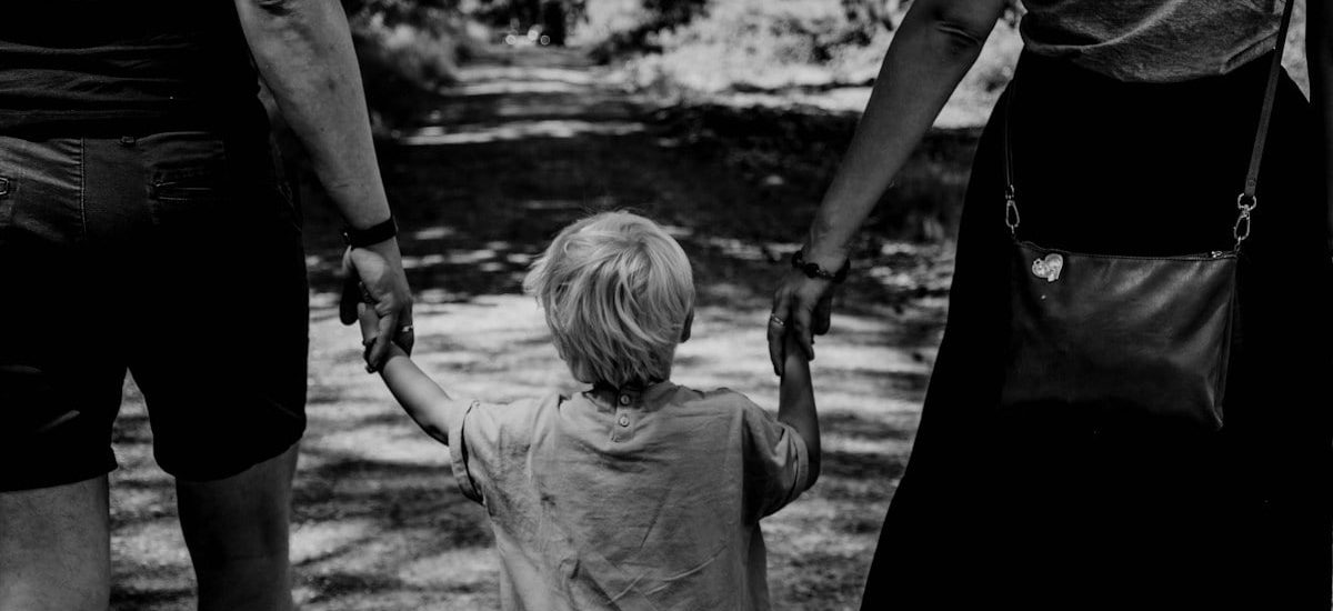 grayscale photo of woman in black dress holding child in black shirt